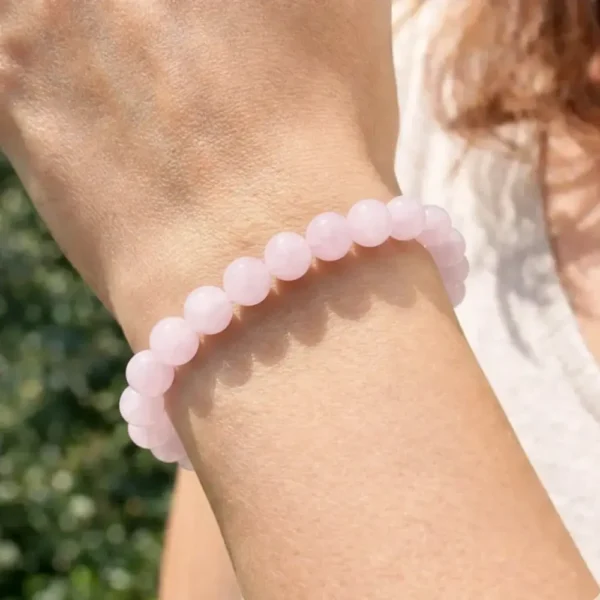 Bracelet en kunzite naturelle rose pastel aux reflets lilas porté au poignet d'une femme
