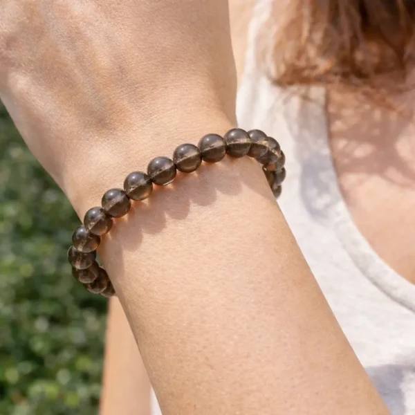 Bracelet en Quartz Fumé naturel porté au poignet, révélant la transparence des pierres et le soin apporté à la confection artisanale.