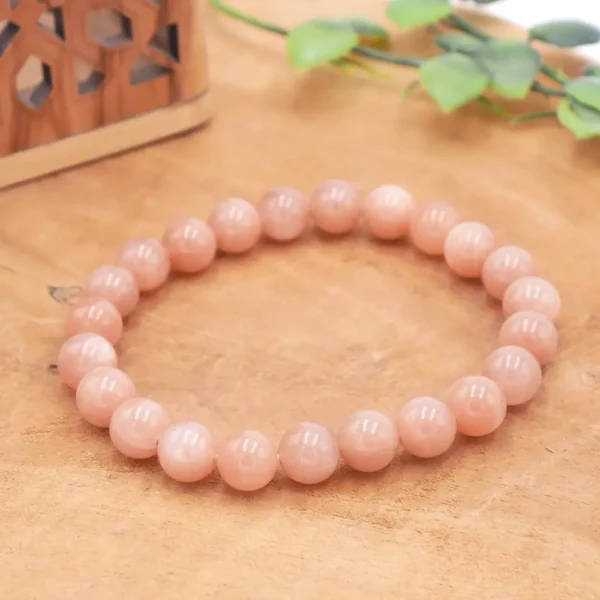 Bracelet en Pierre de Soleil pêche naturelle, perles aux reflets pailletés orangés et inclusions scintillantes montées sur fil résistant.