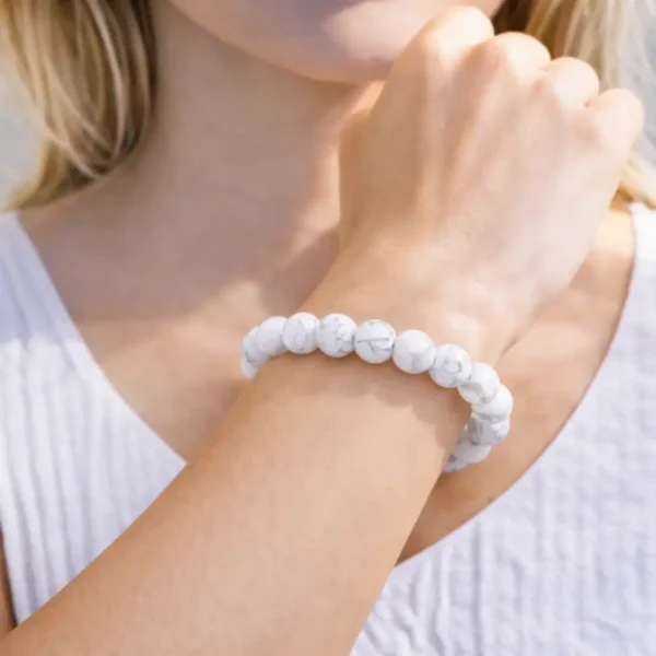 Bracelet en Howlite naturelle porté au poignet, perles d'un blanc opaque avec veines grises effet marbre, montage artisanal de qualité.