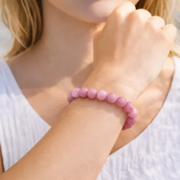 Bracelet en Rhodonite rose naturelle porté au poignet, perles aux nuances vieux rose et bois de rose, montage artisanal de haute qualité.
