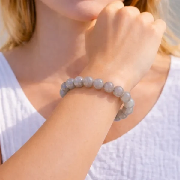Bracelet en pierre de lune grise naturelle aux reflets soyeux porté par un mannequin