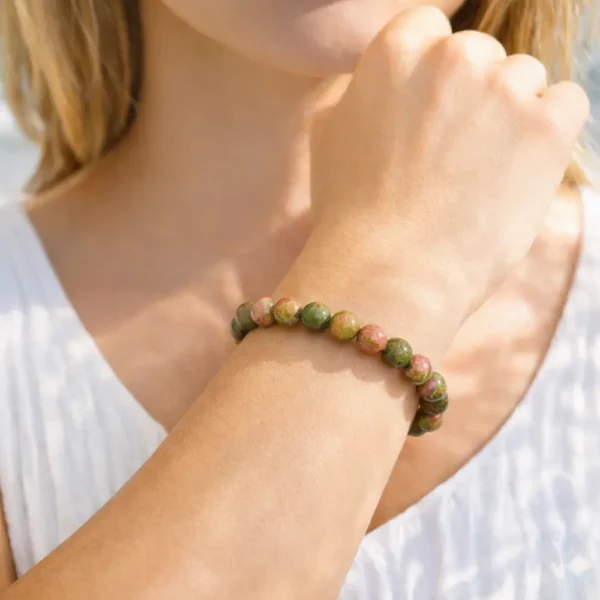 Bracelet en Unakite naturelle porté au poignet, mettant en évidence les nuances de l'épidote verte et du feldspath rose sur un bijou artisanal.