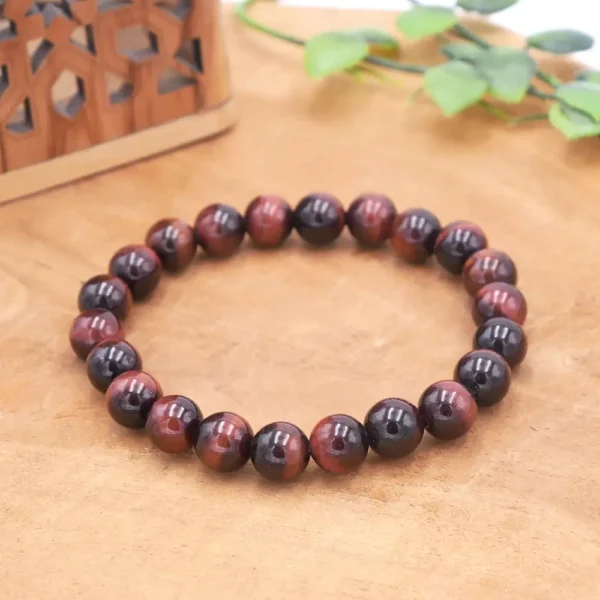 Bracelet en Œil de Taureau naturel, perles rouge brique aux reflets soyeux et chatoyants montées sur fil élastique haute résistance.