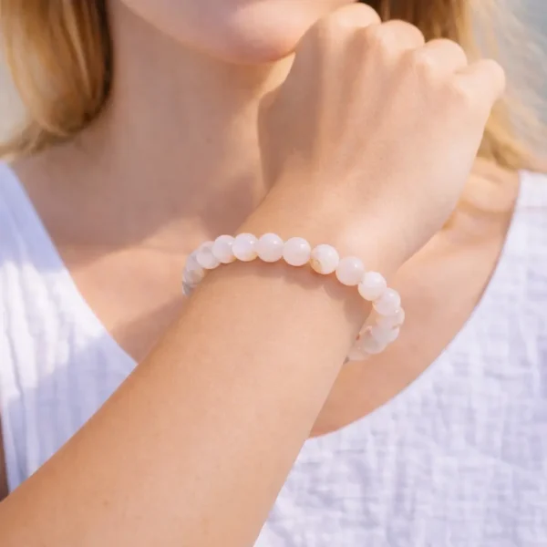 Bracelet en Agate Fleur de Cerisier naturelle sur poignet femme perles translucides aux inclusions rosées et blanches montées sur fil résistant.
