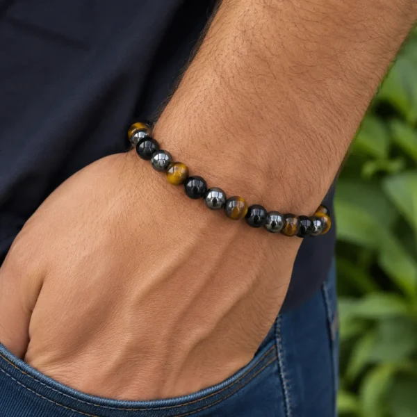 Bracelet triple protection porté au poignet composé de pierres naturelles d'hématite, obsidienne noire et œil de tigre.